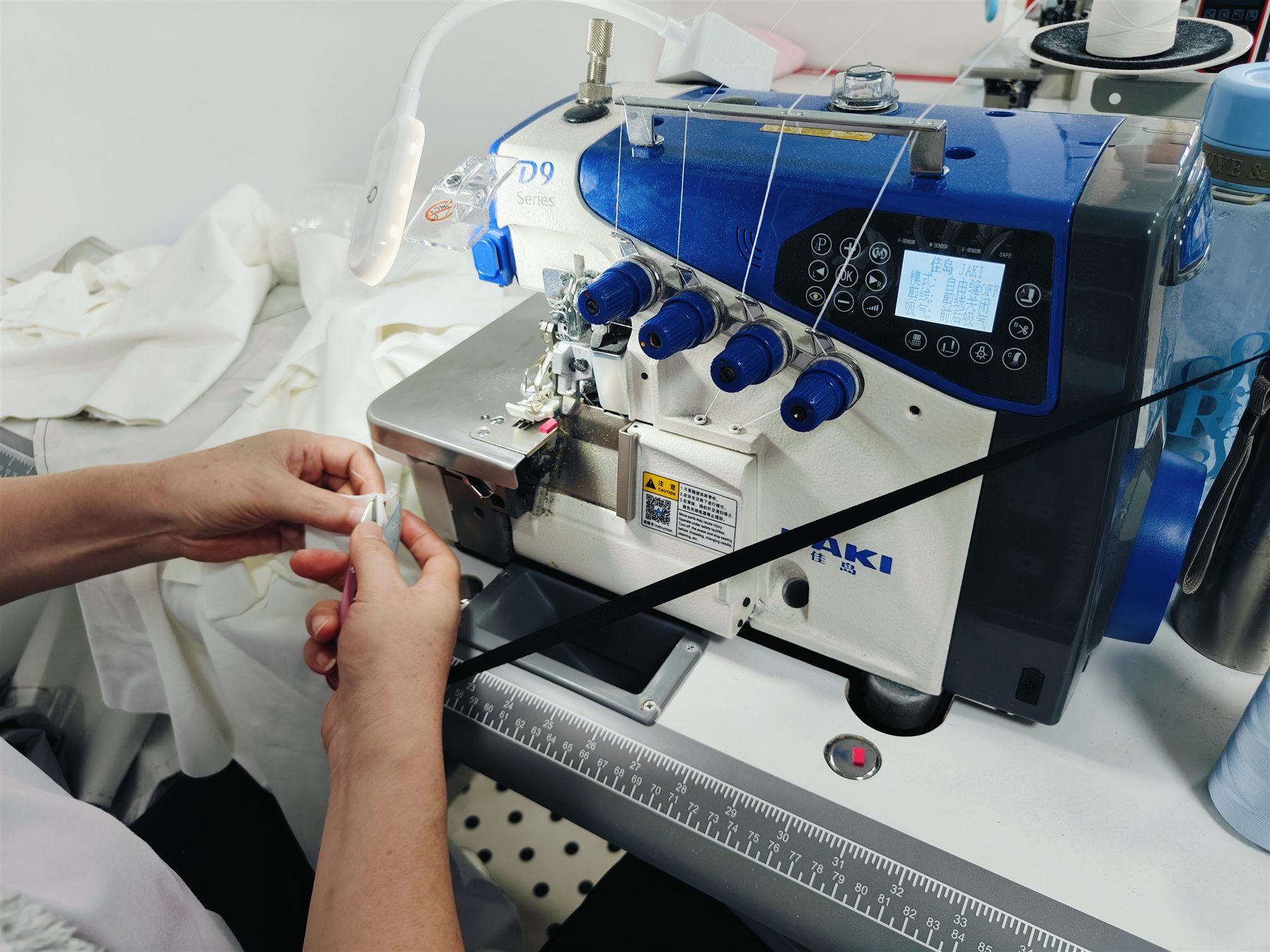 Operator preparing fabric at an overlock sewing machine