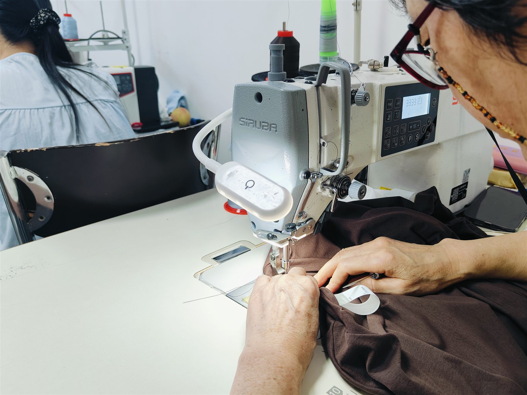Garment worker sewing knit fabric at an industrial machine