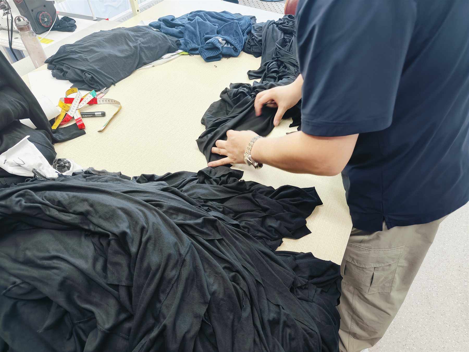 Operator sewing black knit fabric with specialised industrial equipment