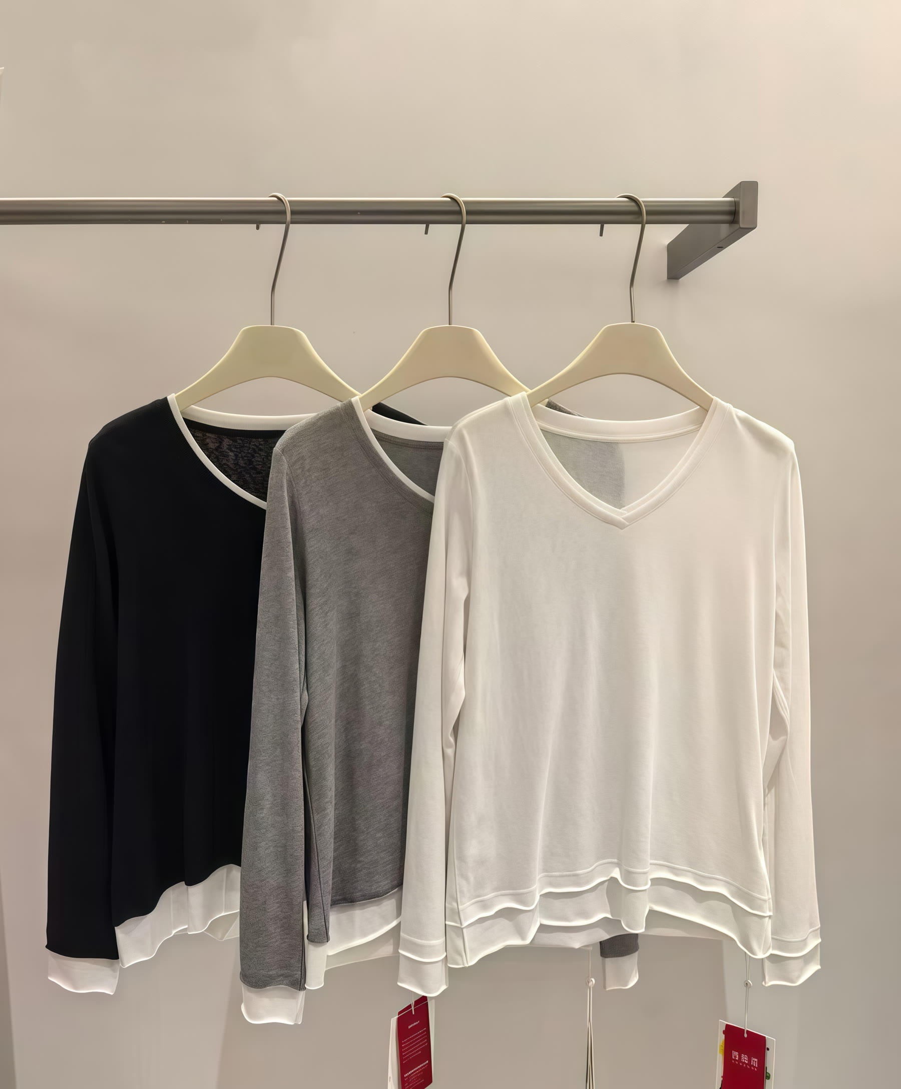 Black, grey and white long-sleeve V-neck tops displayed on hangers